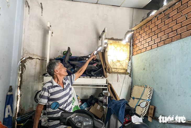 40 nhà dân gần công trình xây bờ kè 'bỗng nhiên' bị nứt toác - Ảnh 1. Ông Nguyễn Văn Quang (69 tuổi, ngụ tại số nhà 28 Phú Định) chỉ cho phóng viên thấy những vết nứt toác khắp căn nhà. Ông Quang đã dùng xi măng để trám tạm nhưng vẫn không ăn thua - Ảnh: TIẾN QUỐC